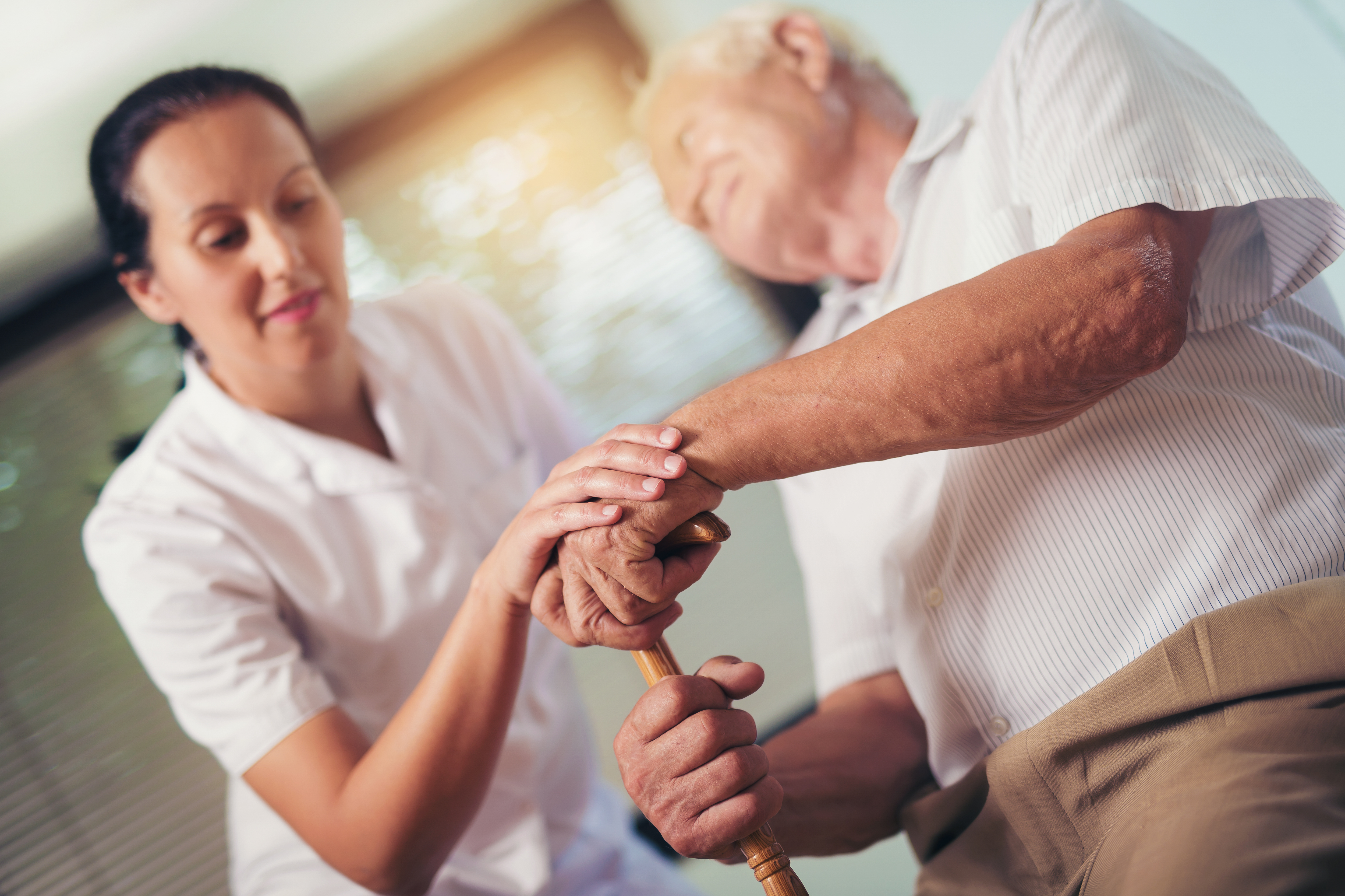 Practitioner helping elderly man with cane
